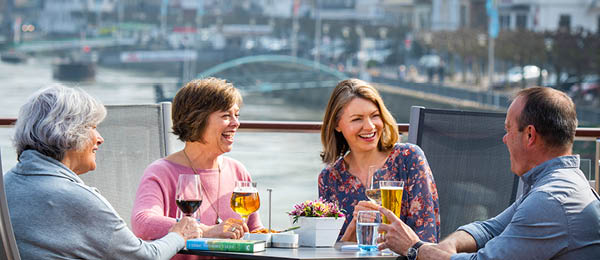 Two older couples enjoying drinks at an outside table