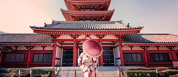 Woman with umbrella in front of Japanese Temple