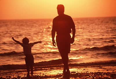 father and child walking on the beach